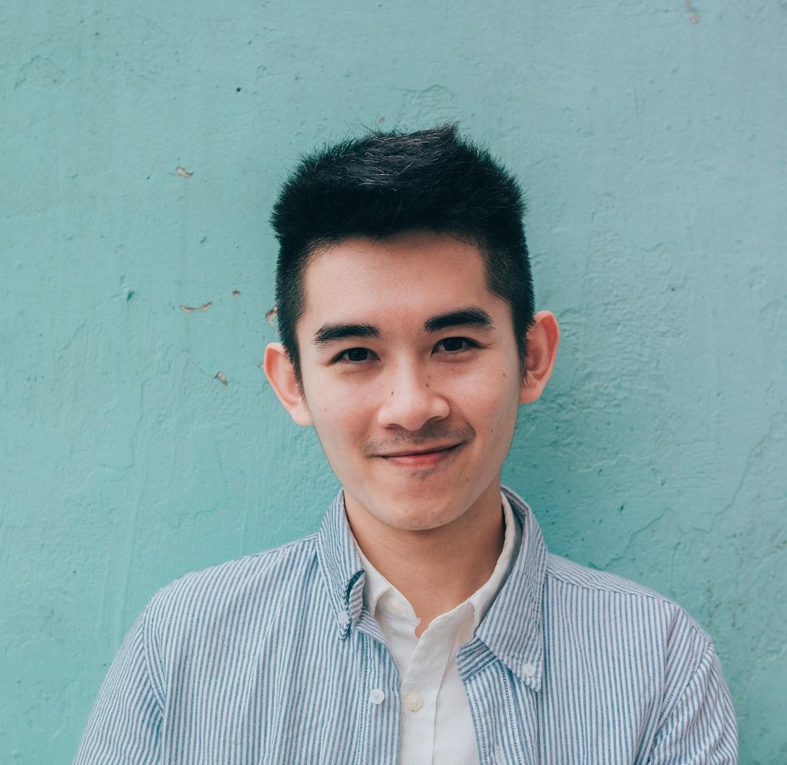 man wearing blue white stripe shirt leaning on the wall