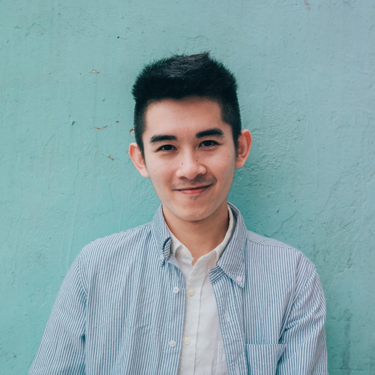 man wearing blue white stripe shirt leaning on the wall